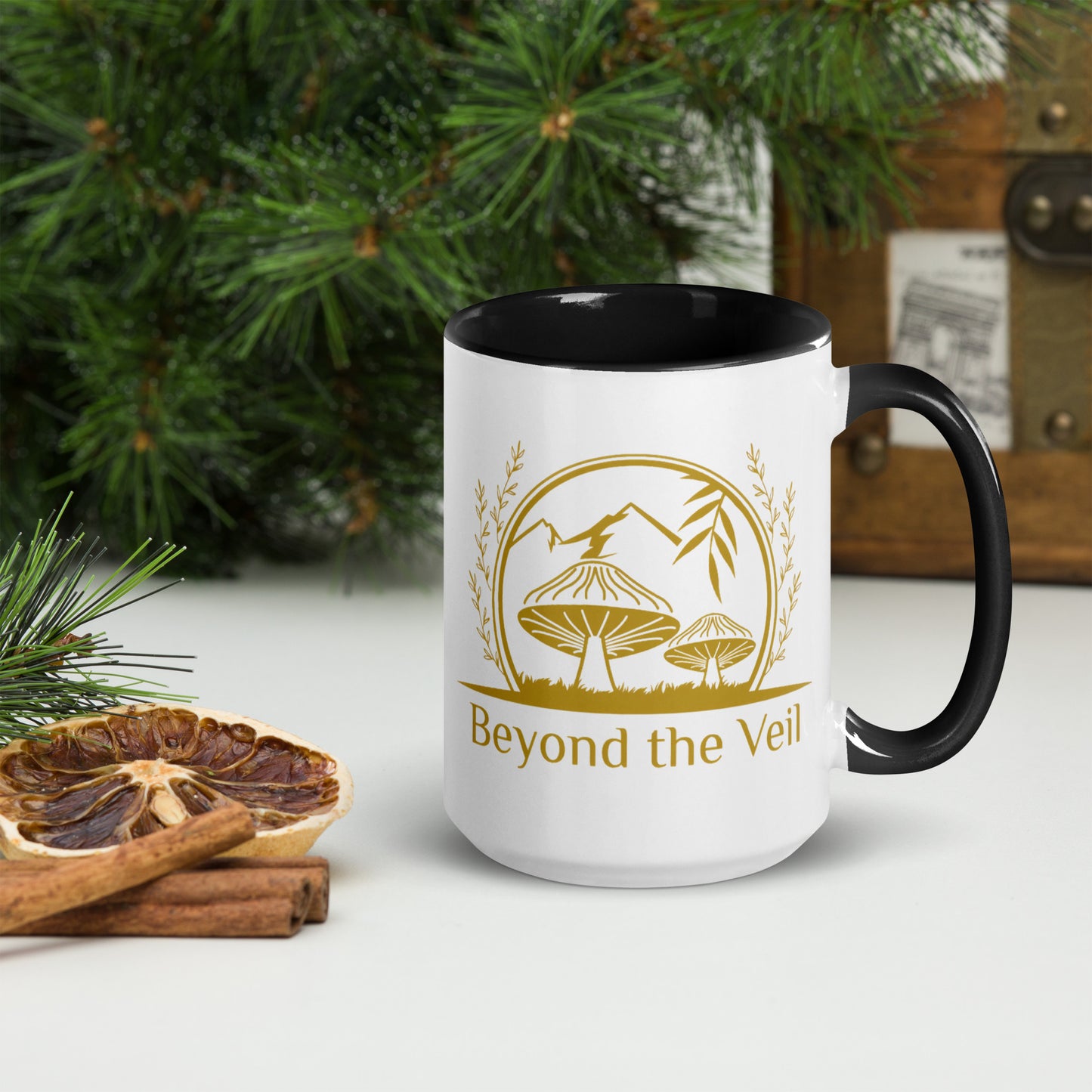 White mug with black interior and handle, featuring a gold logo and text 'Beyond the Veil' on a Christmas Background